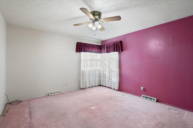 carpeted spare room featuring ceiling fan and a textured ceiling