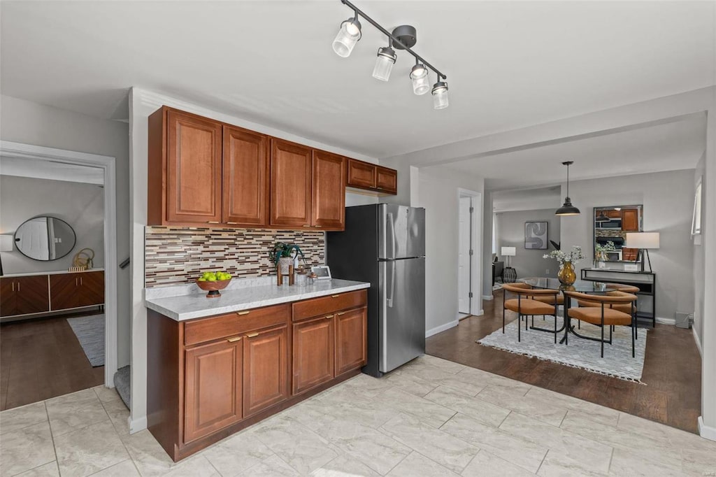 kitchen featuring stainless steel fridge, backsplash, and decorative light fixtures