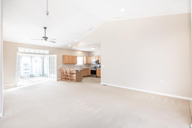 unfurnished living room with ceiling fan, light colored carpet, and lofted ceiling