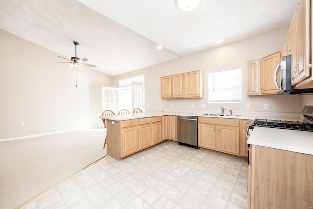 kitchen featuring lofted ceiling, light brown cabinetry, sink, kitchen peninsula, and stainless steel appliances