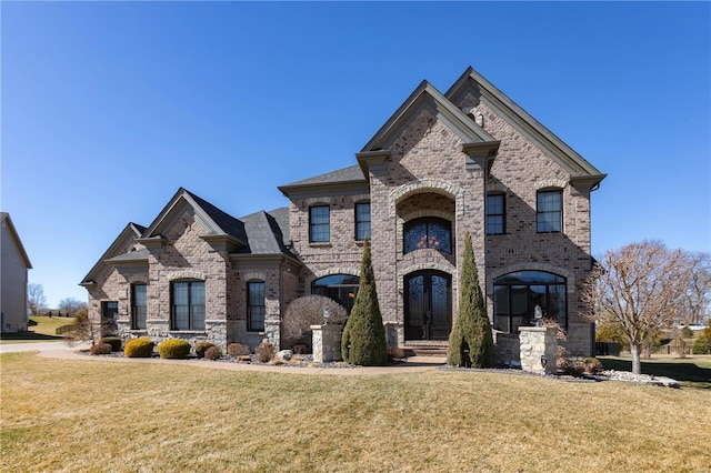 french country home featuring a front lawn, french doors, and brick siding