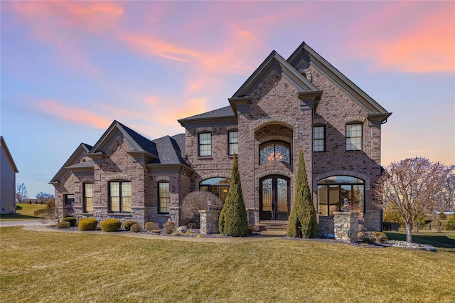 view of front of property with brick siding, a front lawn, and french doors