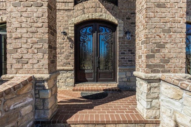 property entrance featuring french doors and brick siding