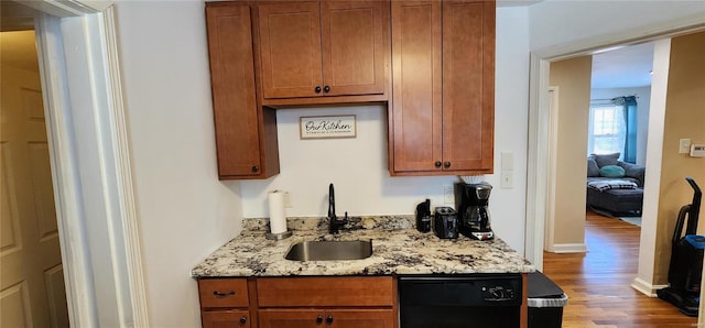 kitchen with light stone countertops, black dishwasher, sink, and light hardwood / wood-style floors