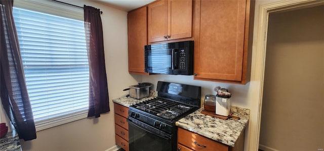 kitchen with light stone counters, plenty of natural light, and black appliances