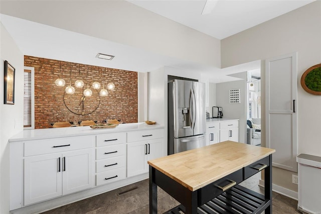 kitchen featuring white cabinetry, brick wall, pendant lighting, and stainless steel fridge with ice dispenser