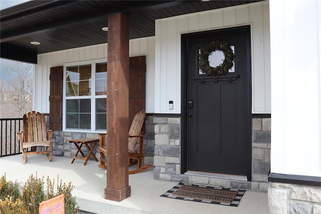 entrance to property with a porch and stone siding