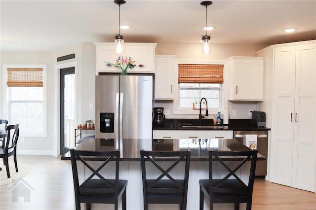 kitchen featuring white cabinets, a breakfast bar area, stainless steel appliances, and a sink