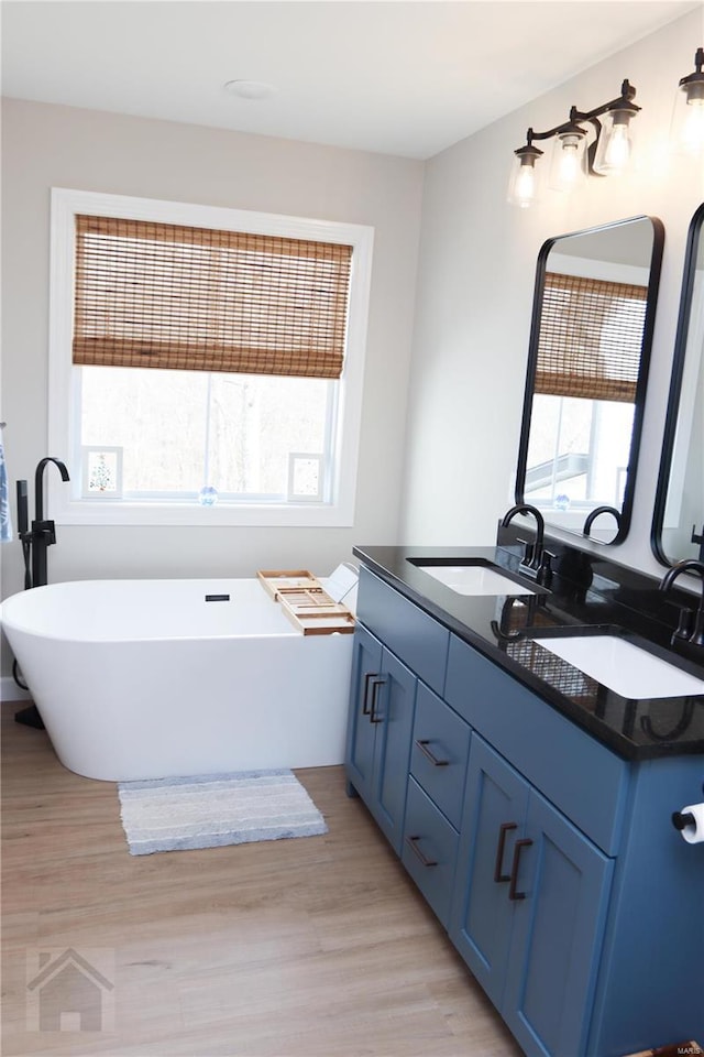 full bathroom featuring a healthy amount of sunlight, a freestanding tub, wood finished floors, and vanity