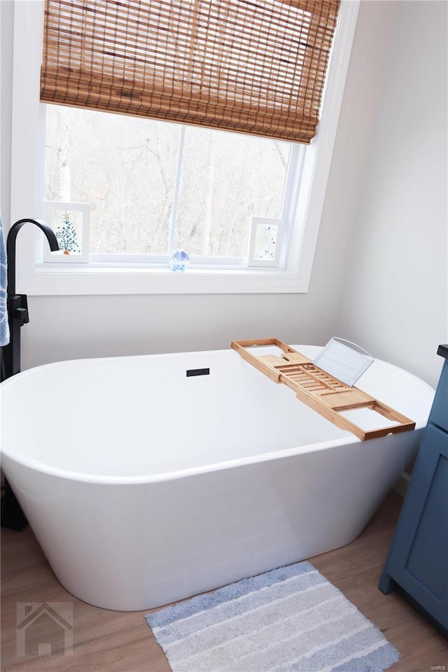 full bath with a freestanding tub and wood finished floors