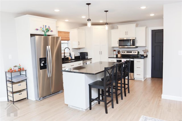 kitchen featuring a breakfast bar area, stainless steel appliances, a sink, a kitchen island, and dark countertops