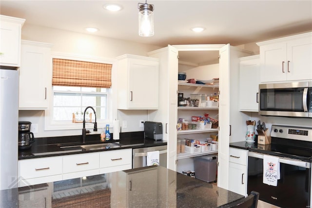 kitchen featuring stainless steel appliances, pendant lighting, white cabinetry, and a sink