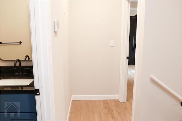 bathroom with a sink, baseboards, and wood finished floors