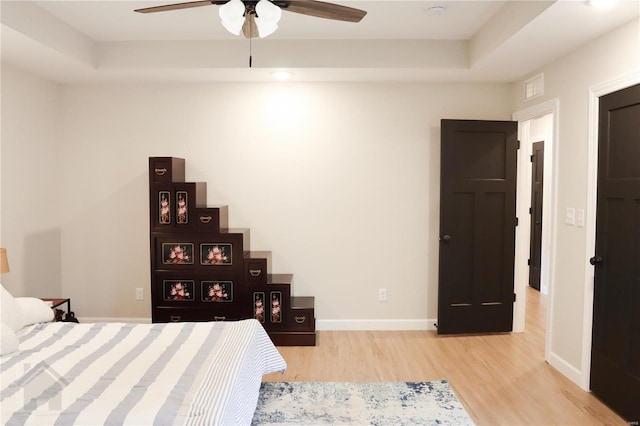 bedroom with baseboards, a tray ceiling, and wood finished floors