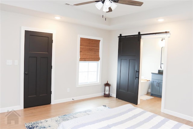 unfurnished bedroom featuring a barn door, light wood-type flooring, recessed lighting, and baseboards