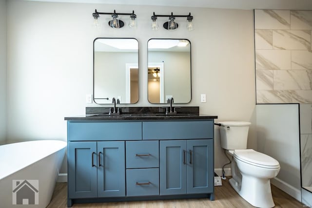 bathroom with a sink, a freestanding bath, toilet, and double vanity