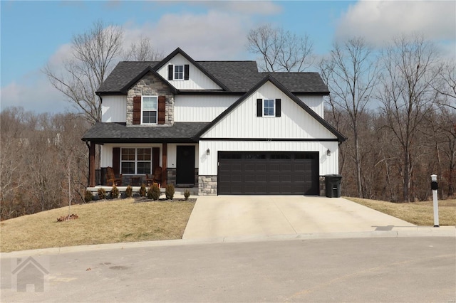 view of front facade with roof with shingles, covered porch, a front yard, stone siding, and driveway