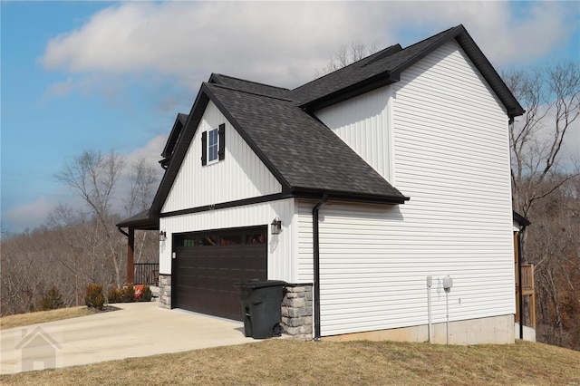 view of side of property with a garage, driveway, and roof with shingles