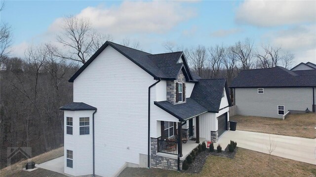 view of side of home with stone siding and concrete driveway