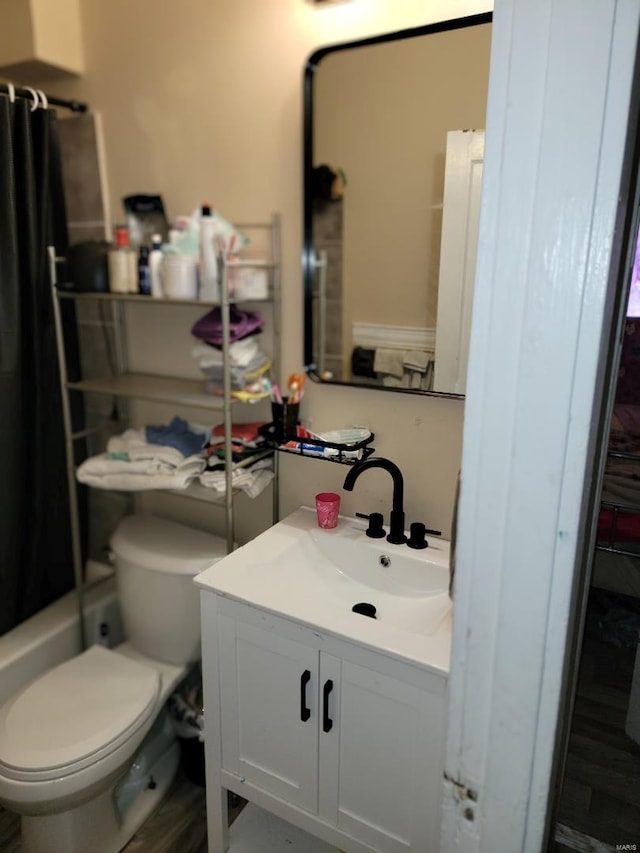 full bathroom featuring hardwood / wood-style flooring, vanity, shower / bath combo with shower curtain, and toilet