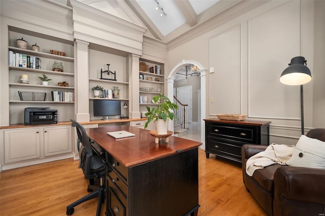 office featuring high vaulted ceiling, decorative columns, beamed ceiling, light hardwood / wood-style flooring, and built in shelves