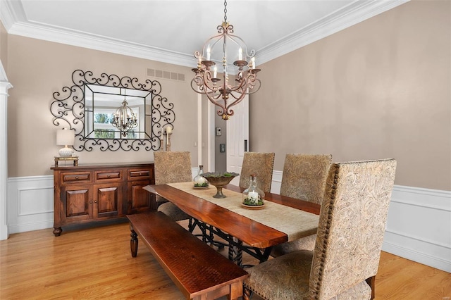 dining space with crown molding, a chandelier, and light hardwood / wood-style flooring