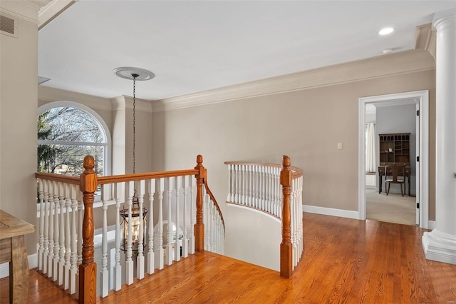 hallway featuring hardwood / wood-style flooring, ornamental molding, and decorative columns