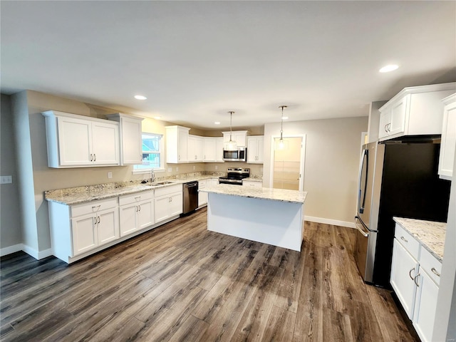 kitchen with pendant lighting, sink, stainless steel appliances, white cabinets, and a kitchen island