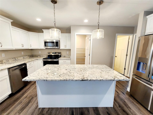 kitchen with a kitchen island, appliances with stainless steel finishes, pendant lighting, and white cabinets