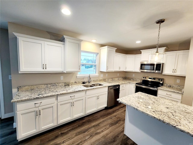 kitchen featuring dark wood-type flooring, sink, appliances with stainless steel finishes, pendant lighting, and white cabinets