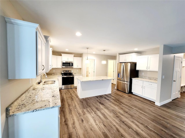 kitchen with a kitchen island, appliances with stainless steel finishes, pendant lighting, white cabinetry, and sink