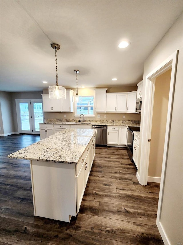 kitchen with white cabinetry, stainless steel appliances, decorative light fixtures, and a kitchen island