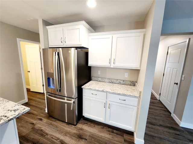 kitchen with white cabinets, dark hardwood / wood-style flooring, stainless steel fridge, and light stone counters