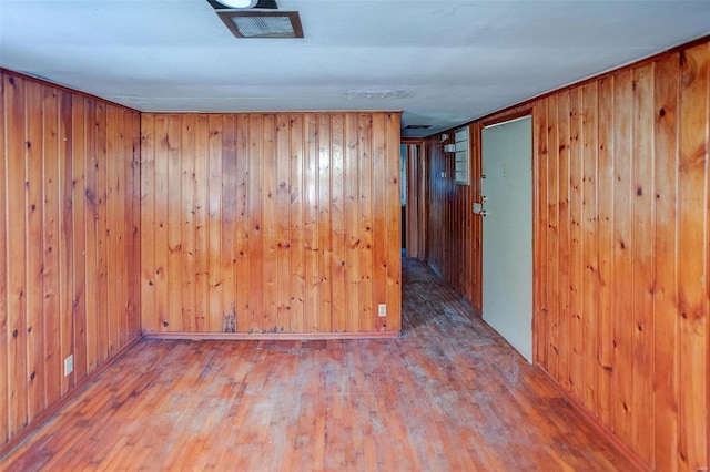 unfurnished room featuring wooden walls and wood-type flooring