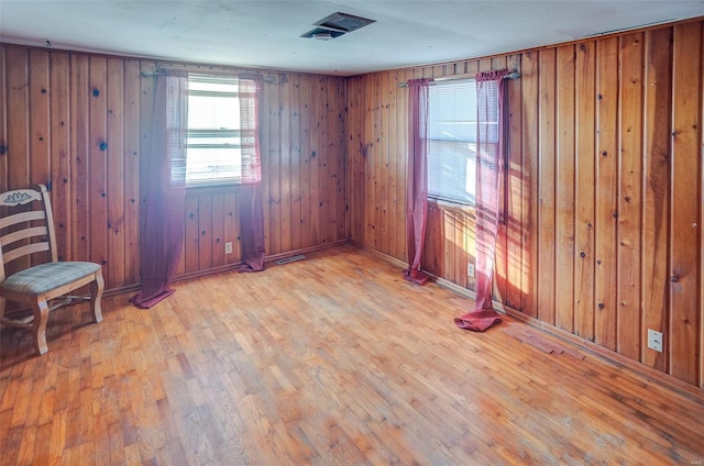 unfurnished room with wood walls and light hardwood / wood-style flooring