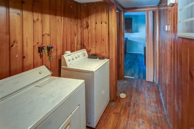 washroom featuring hardwood / wood-style floors, wooden walls, and washing machine and clothes dryer