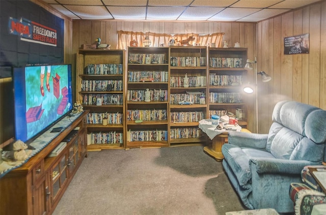 living area featuring carpet and wooden walls