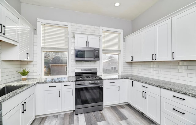 kitchen featuring light stone counters, stainless steel appliances, and white cabinets