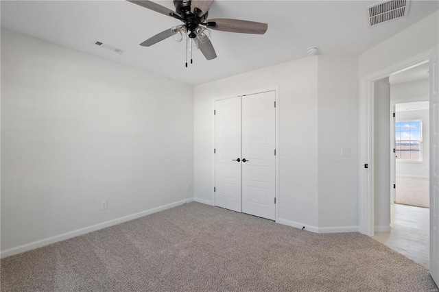 unfurnished bedroom featuring light carpet, ceiling fan, and a closet