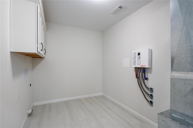 washroom featuring washer hookup, light hardwood / wood-style flooring, and cabinets