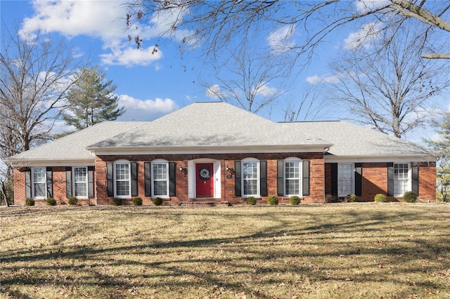 view of front of property featuring a shingled roof, brick siding, and a front lawn