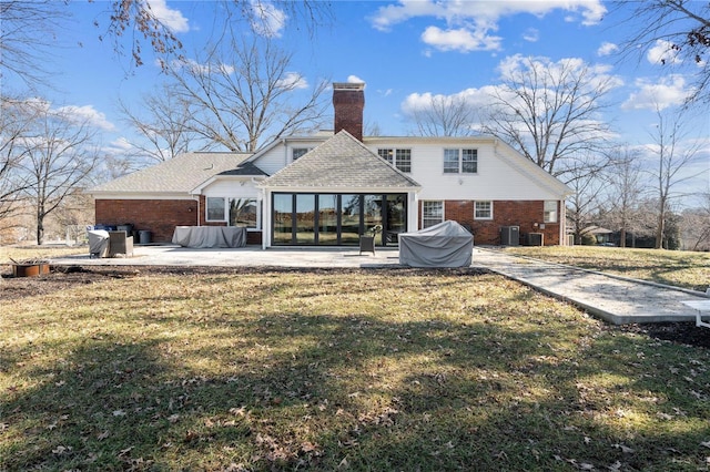 rear view of property featuring a yard, a chimney, a patio, and brick siding