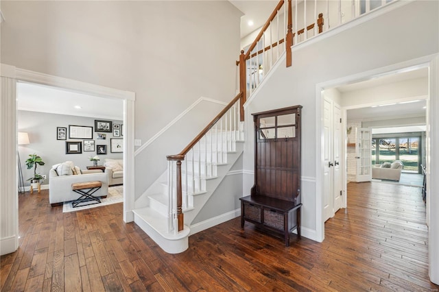 stairway featuring ornamental molding, a towering ceiling, baseboards, and hardwood / wood-style flooring