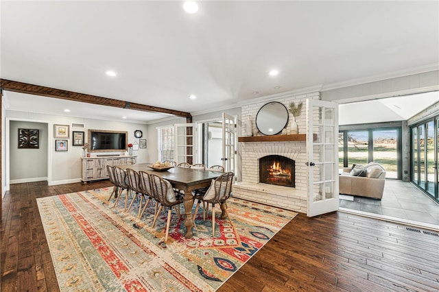 dining room featuring a brick fireplace, hardwood / wood-style floors, crown molding, and french doors