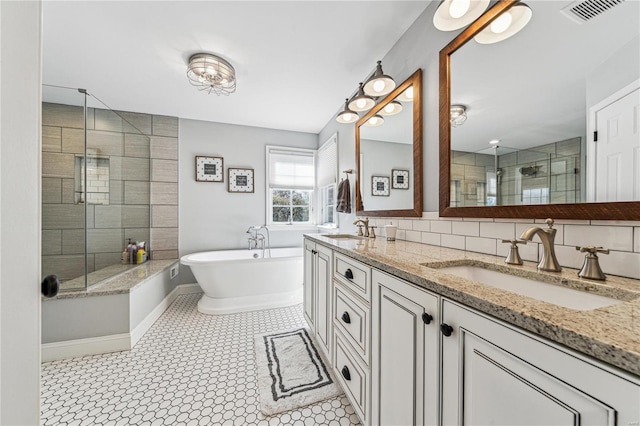 bathroom featuring a shower stall, a freestanding bath, visible vents, and a sink