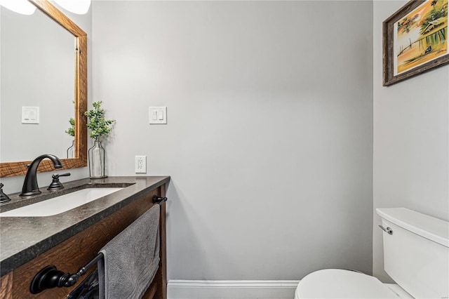 half bath featuring toilet, baseboards, and vanity