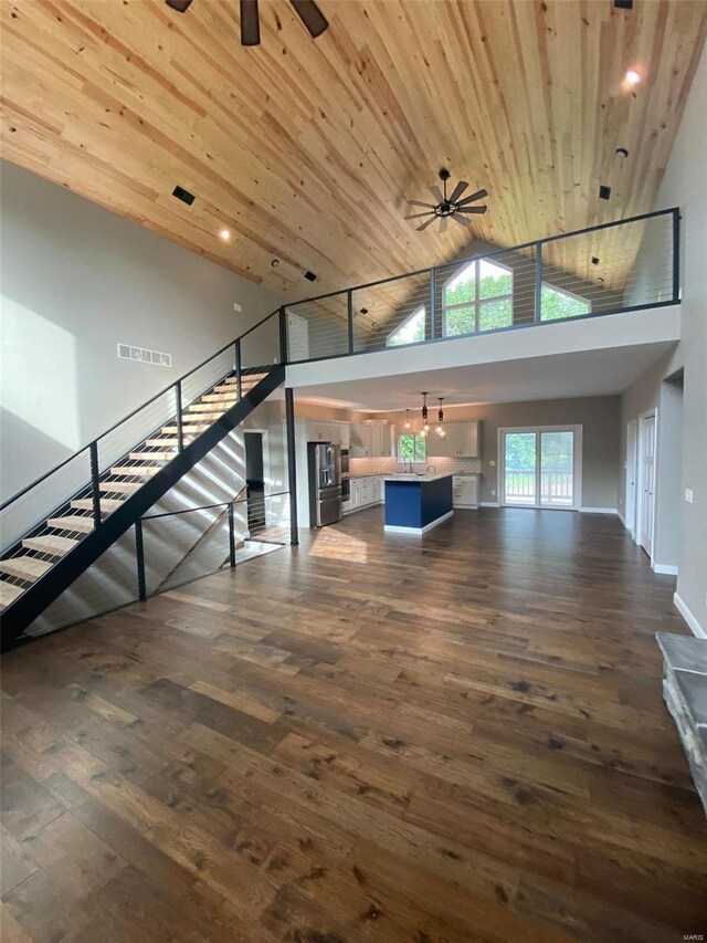 unfurnished living room with dark hardwood / wood-style flooring, high vaulted ceiling, wood ceiling, and ceiling fan