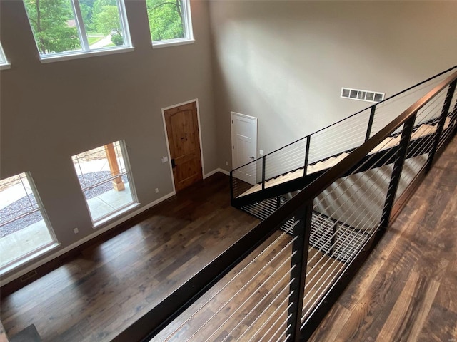 stairs with wood-type flooring and a towering ceiling