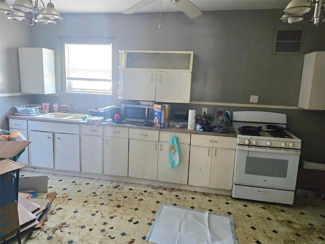 kitchen featuring hanging light fixtures, white cabinetry, sink, and gas range gas stove