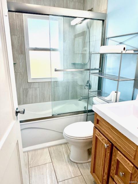 full bathroom featuring toilet, vanity, and shower / bath combination with glass door